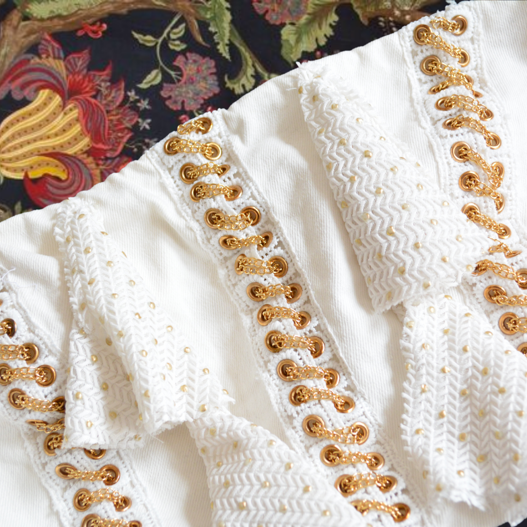 Top blanco con cadenas doradas y olanes